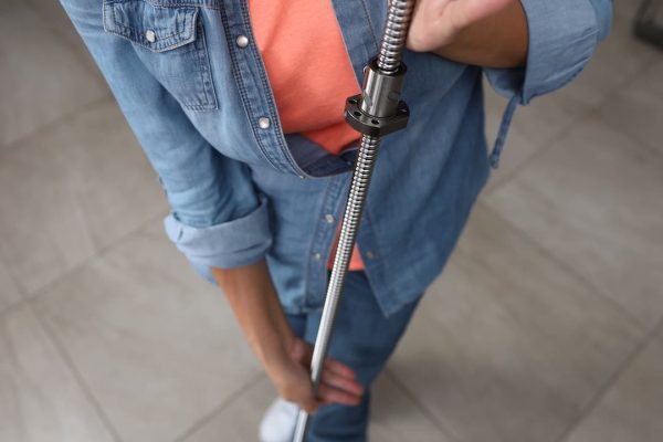 Persona con camisa vaquera y top naranja sosteniendo una varilla espiral de metal en el interior.