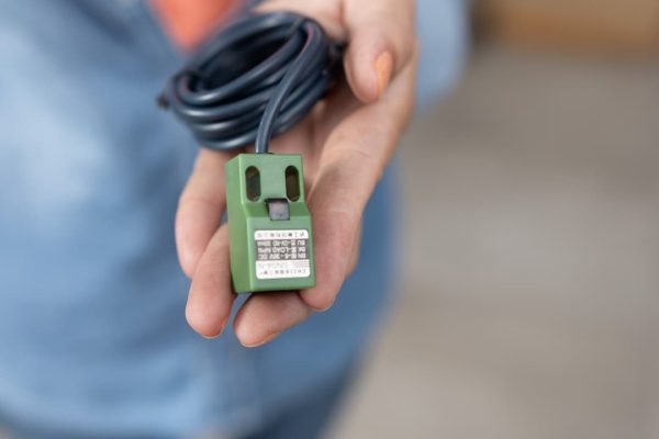 Una persona sosteniendo un sensor verde con un cable.