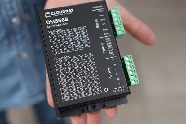 Una persona sostiene un controlador de micropasos Cloudray DM556S en su mano.