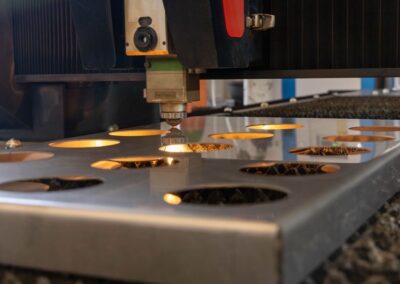 Una máquina de corte por láser CNC corta orificios circulares en una lámina de metal.